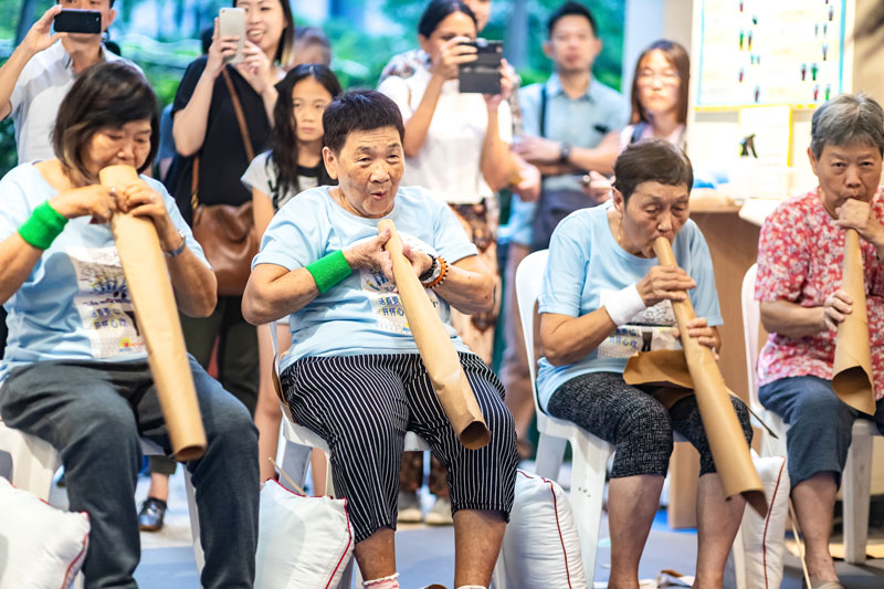 Four senior citizens having fun using rolled brown paper as trumpets. Photo Credit - Zinkie Aw