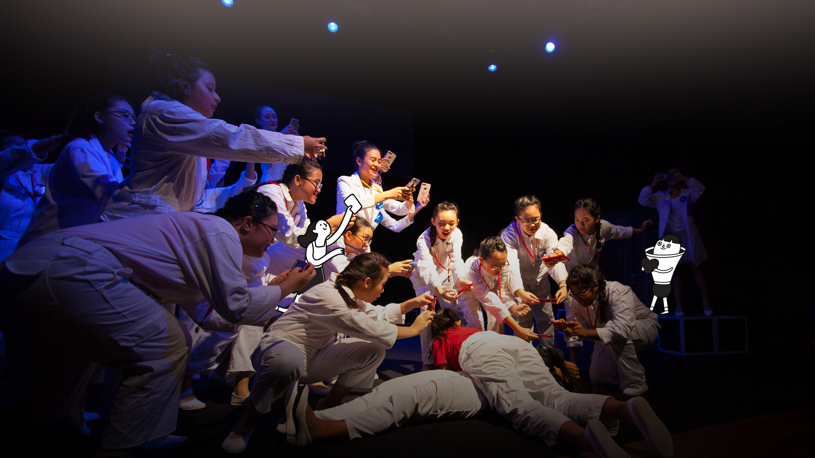 Group of actors wearing white jumpsuits crowding together and using their phone to take a picture of two people lying on the ground