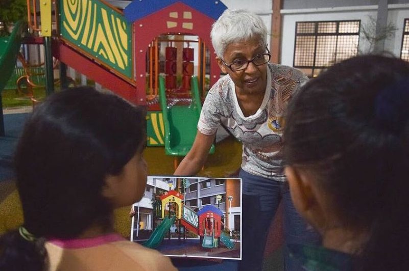 Janet Pillai (middle) showing two children a photograph of the playground