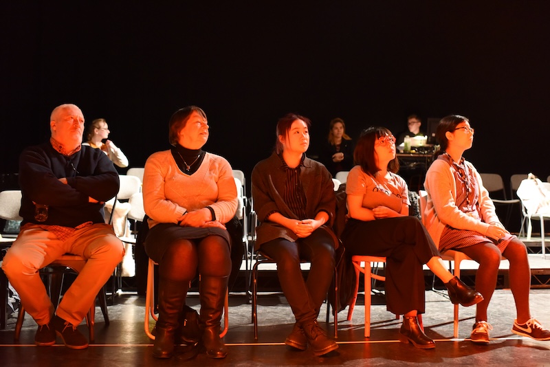 Five people seated in a line, all looking towards the right