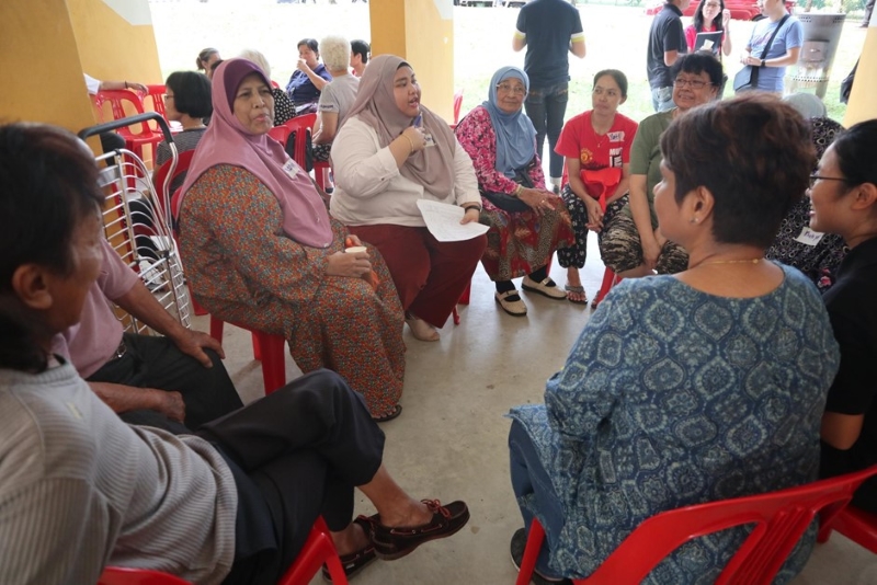 A group of people, of Southeast Asian ethnicity, seated on red chairs in a loose circle. Photo courtesy of Beyond Social Services