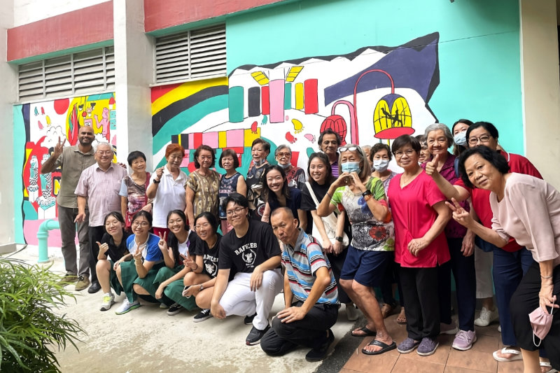 Residents and members of the Raffles Institution art club standing in front of the mural painted outside Allkin Community @ Ang Mo Kio 414