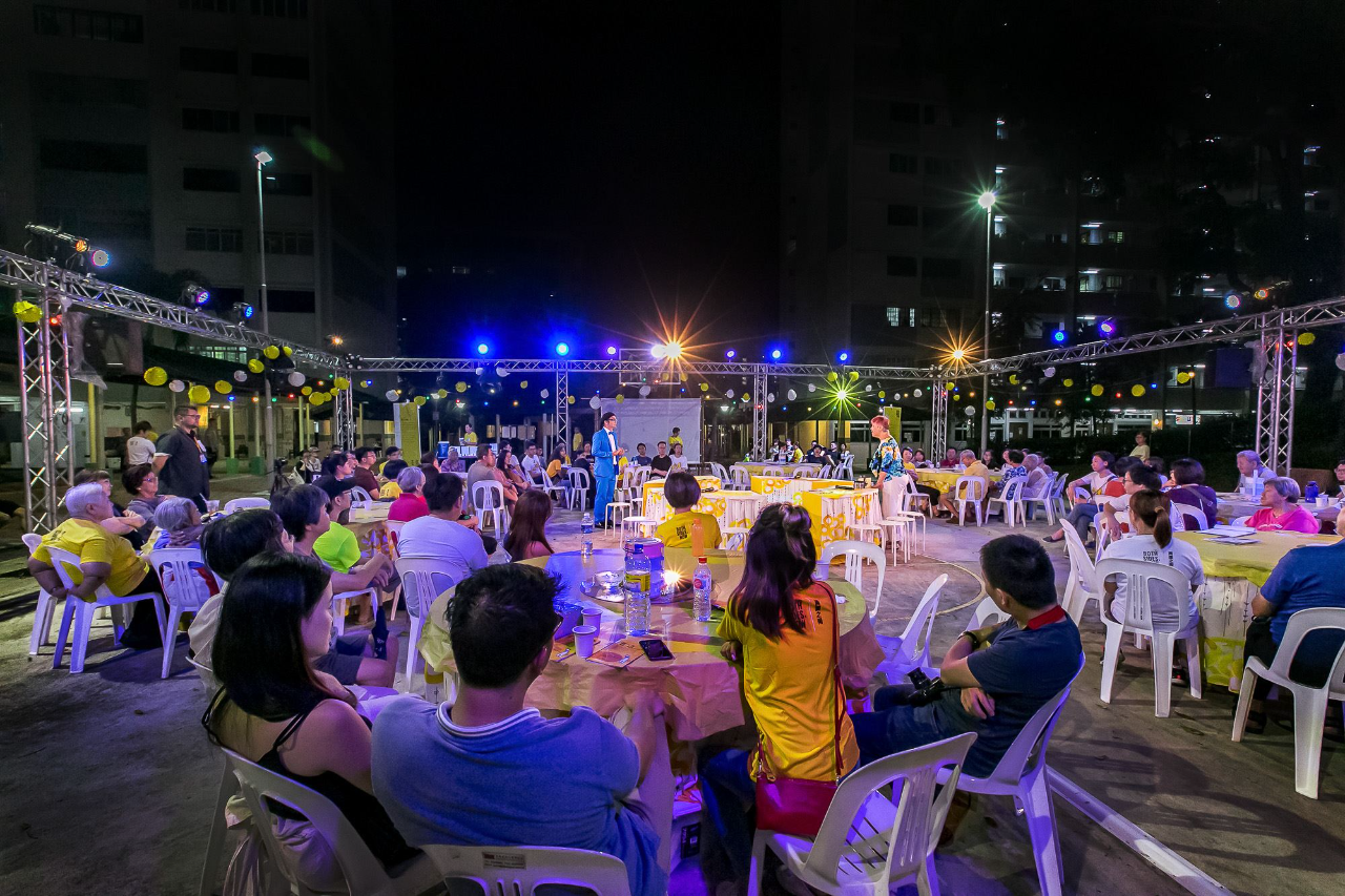 Crowd seated at multiple round tables watching a performance