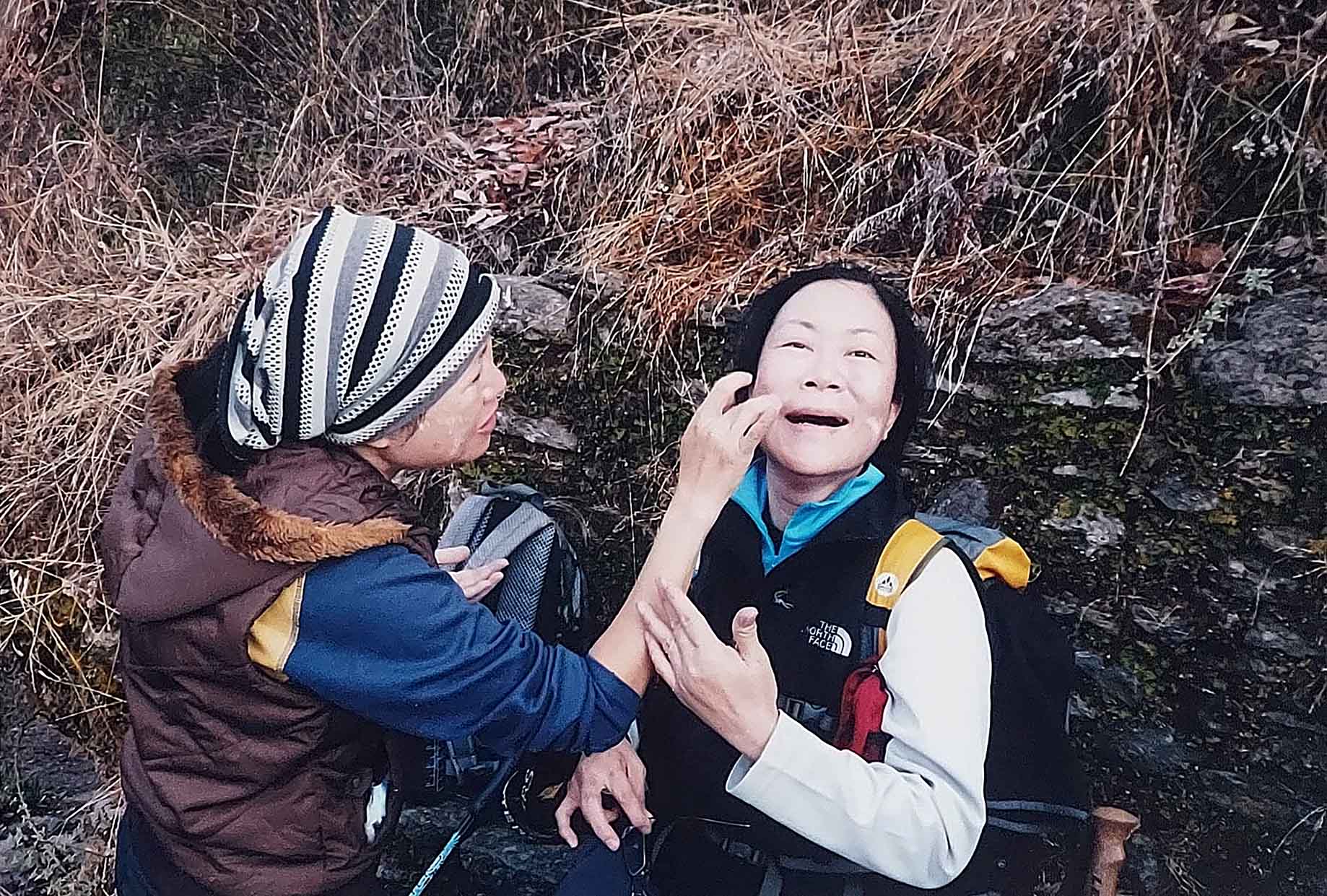 Shirley’s sister applies sunblock on Shirley’s face on a trek.