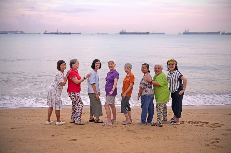 8 seniors facing each other in front of a sea landscape