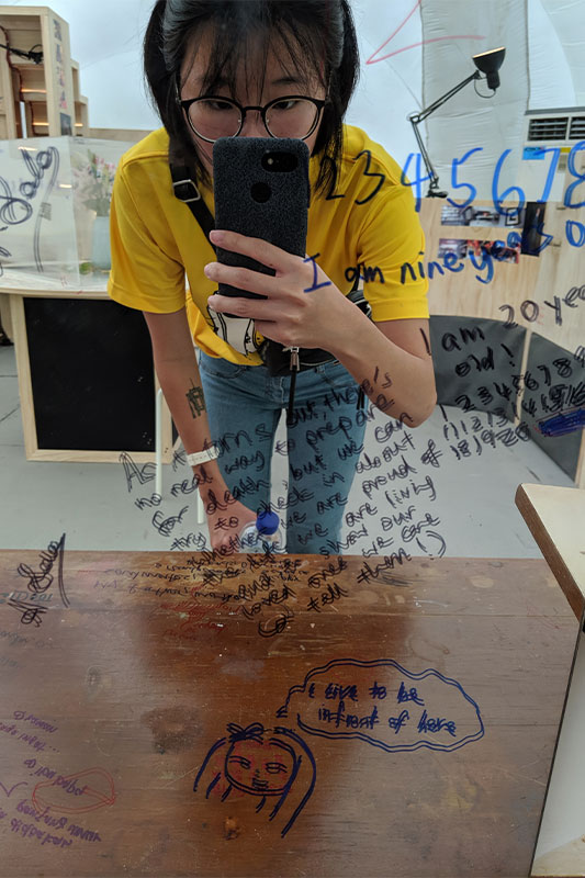 A mirror where residents have written their well wishes, includes Lexie's reflection