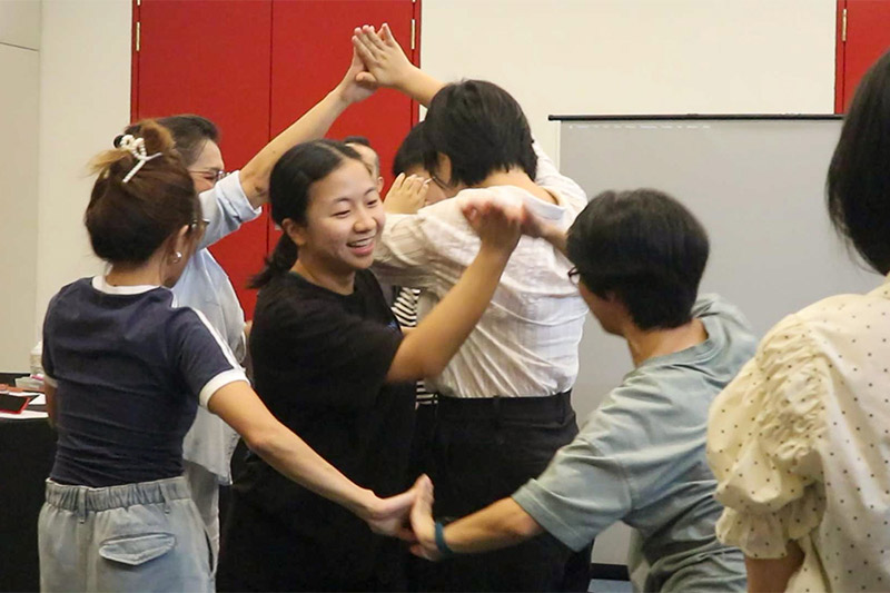 2 people presenting a mahjong paper filled with categorised post-it notes in a workshop setting